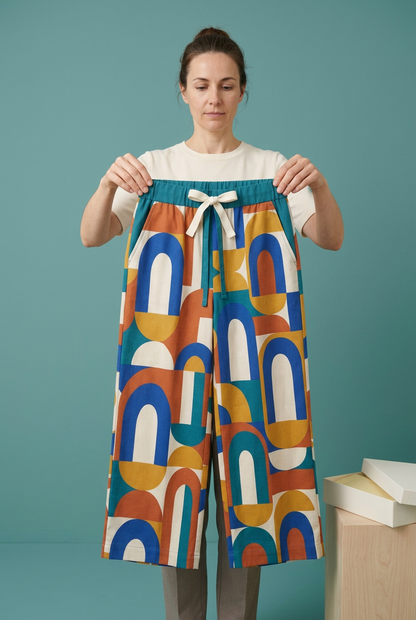 European-style model holding geometric trousers by waistband